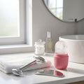 Pink ice roller, steel gua sha and roller on a bathroom counter